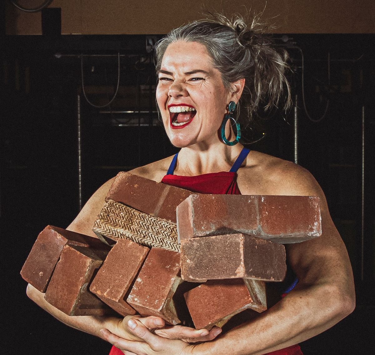 Charmaine holds a pile of bricks in a promo image for Strong Enough